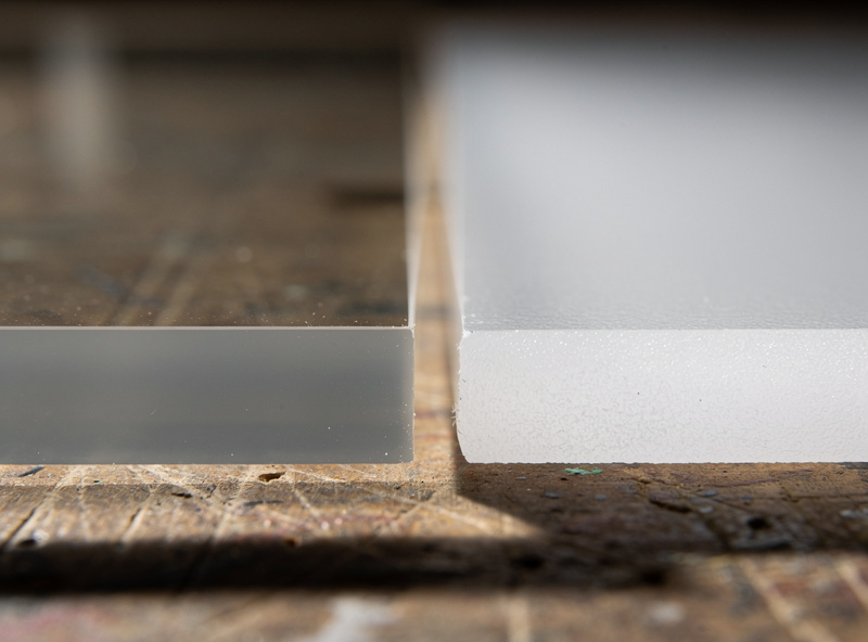 Two laser cut acrylic edge samples side by side showing cast acrylic with clean polished edge on the left and extruded acrylic with hazy white edge on the right