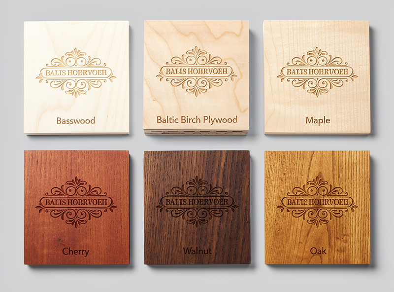 Six different wood samples laser engraved with the same logo design arranged in a grid showing different burn contrasts and grain patterns