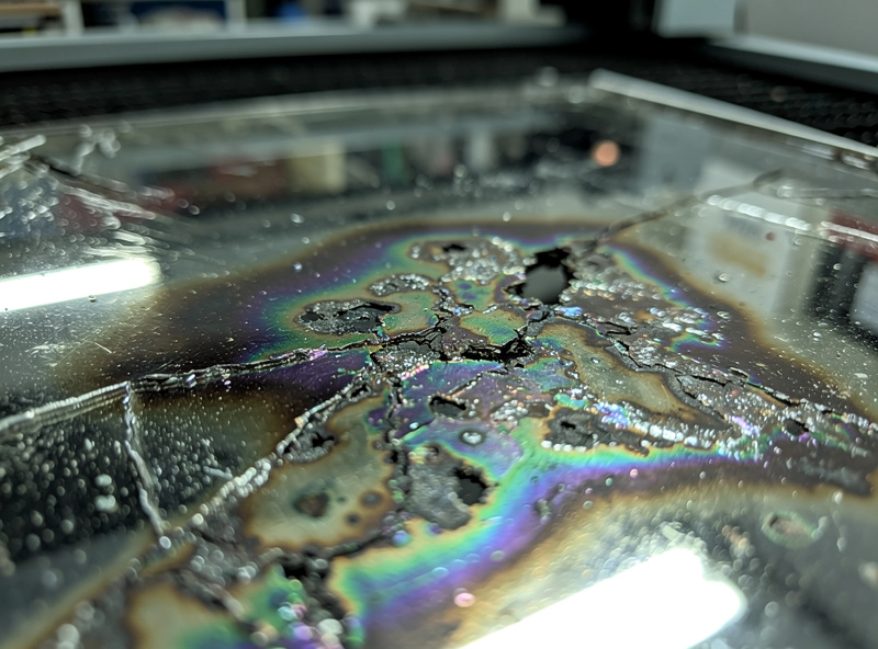 Damaged corroded laser cutter mirror and laser tube showing visible chemical etching from PVC cutting damage with corrosion patterns