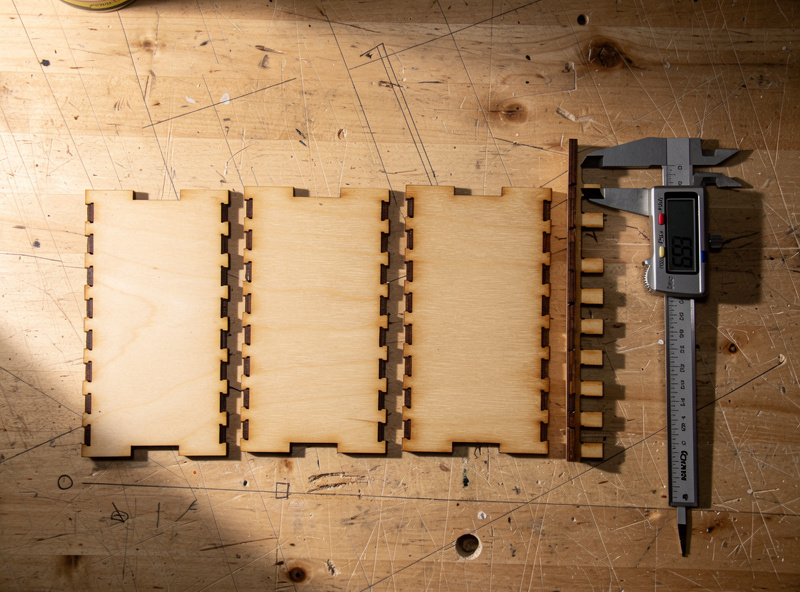 A flat layout of laser-cut box panels with finger joints laid out on a workshop bench ready for assembly