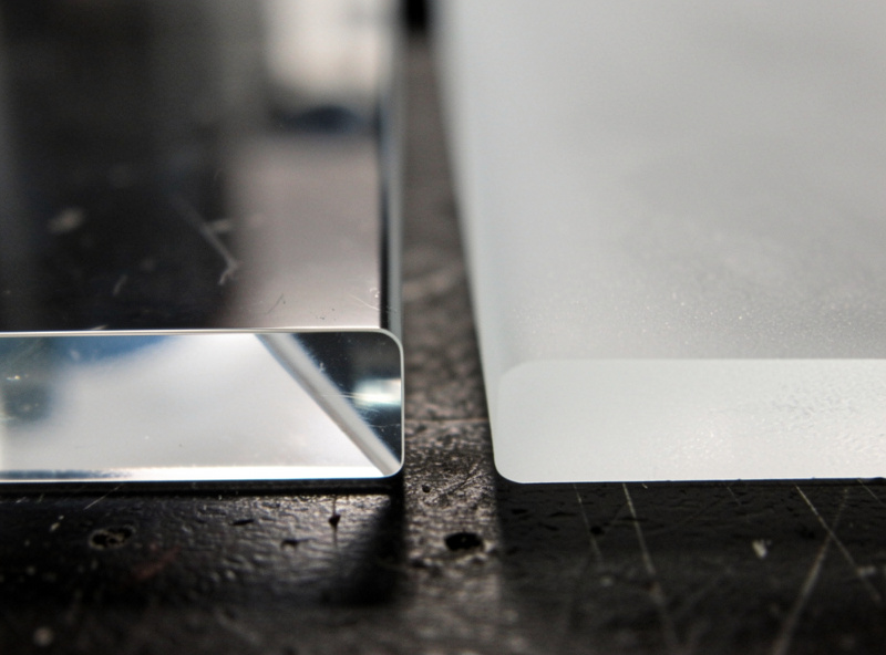 Two laser-cut acrylic edge samples side by side, cast acrylic with a clear polished edge on the left and extruded acrylic with a hazy white edge on the right