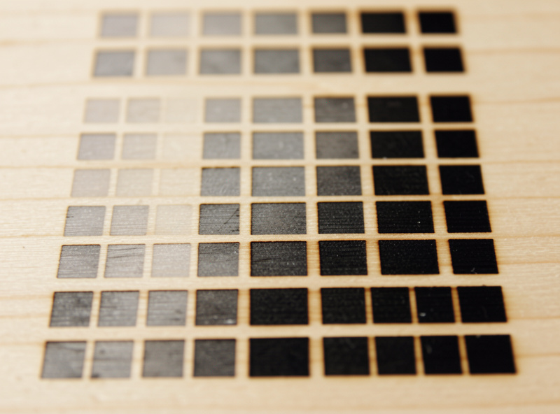 A laser power and speed test grid burned into pale maple showing graduated tonal swatches