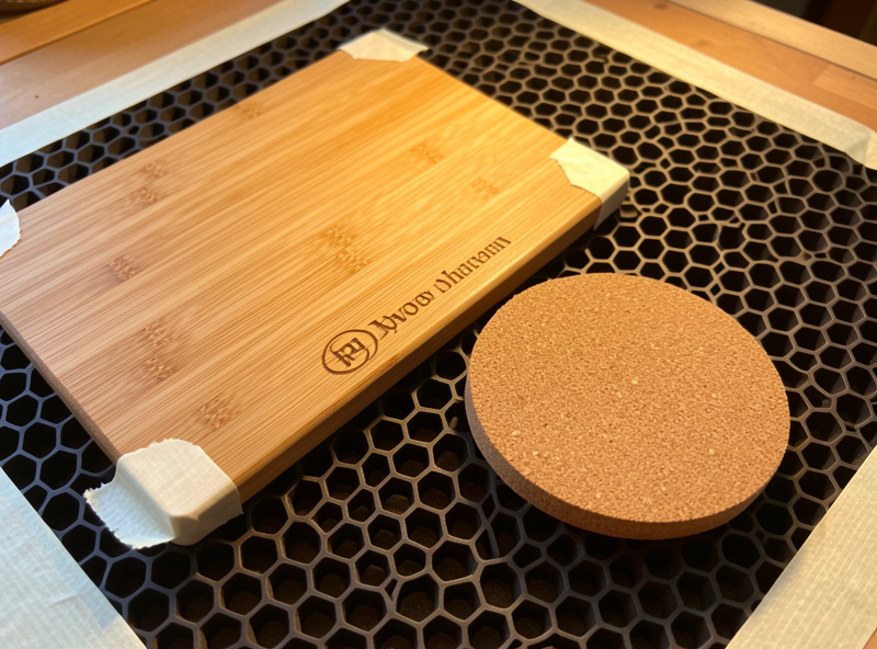 Engraved bamboo board and cork coaster on the laser bed with scorch-control masking