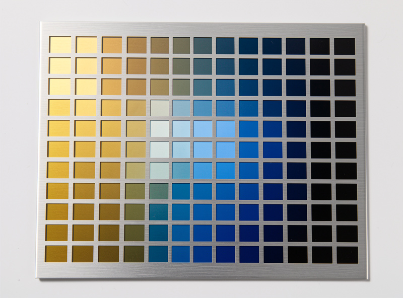 Stainless steel laser test card grid with squares ranging from gold to blue to black